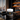 A jar of Ferkaux Clay Mask for Pores & Blackheads sits on a polished black marble desk in a luxury office setting with a city view window and warm wood shelving in the background.
